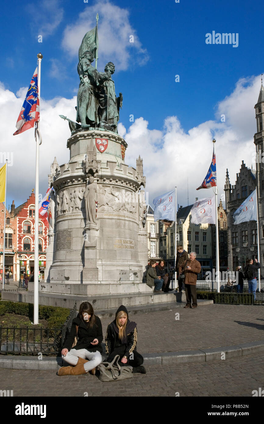 Two girls sit at the foot of the heroic statue of Jan Breydel and Pieter De Coninck in the Markt, Brugge, Belgium Stock Photo