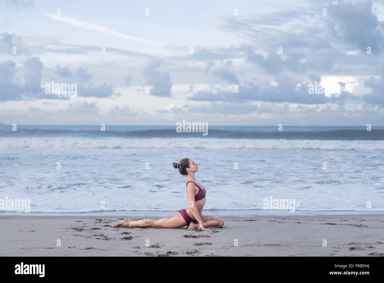 side view of beautiful young woman practicing yoga in sss pose on ...