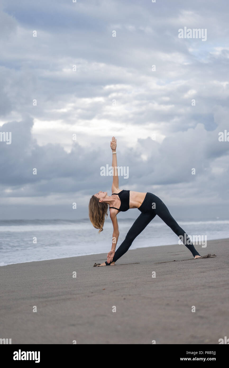 fit young woman practicing yoga in Triangle pose (Trikonasana) on ...