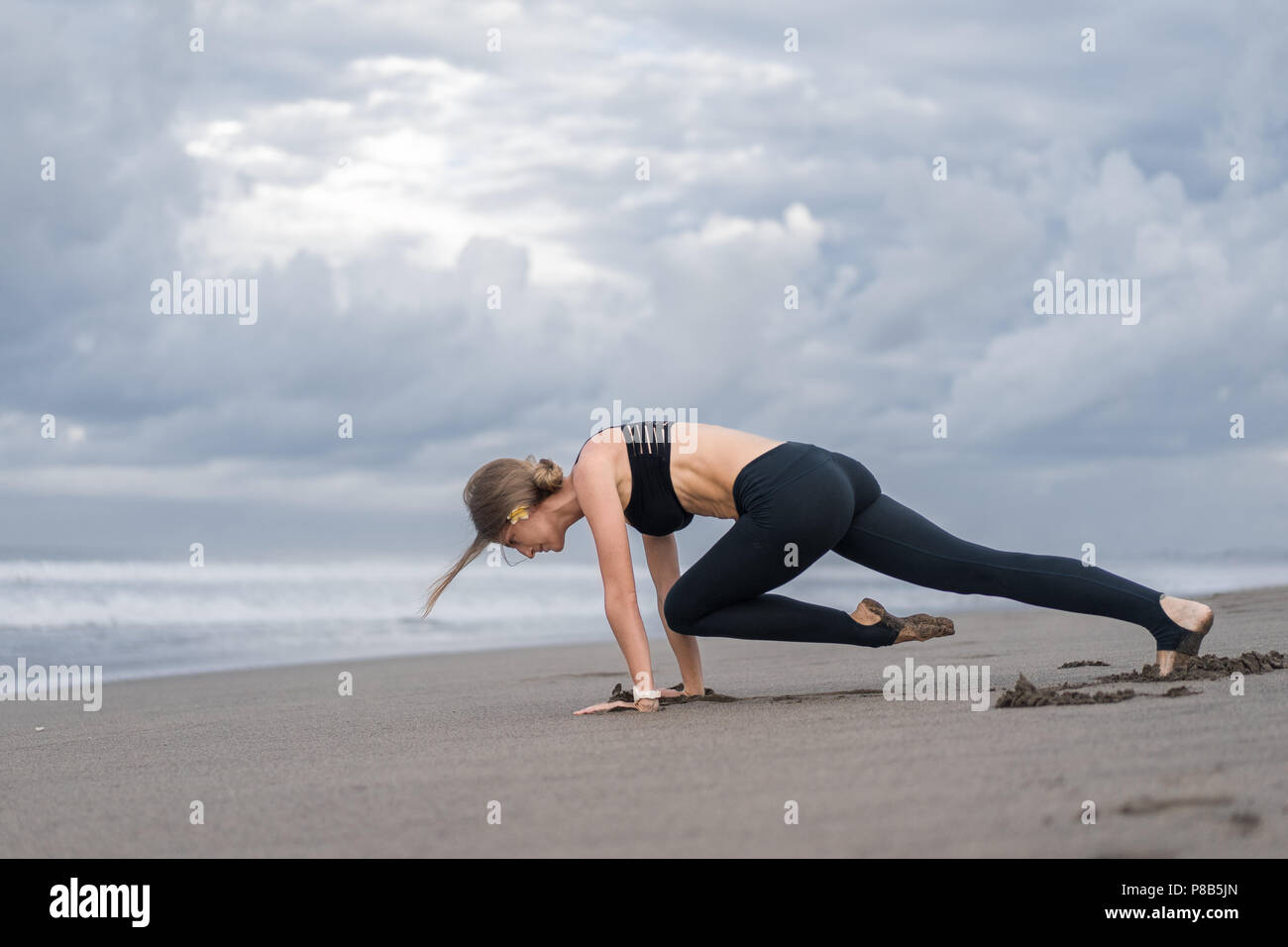 athletic young woman practicing yoga on seashore Stock Photo - Alamy