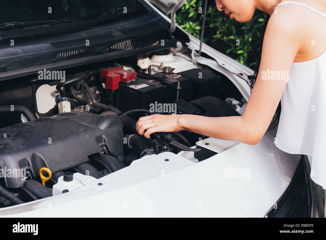 Asian woman checking her broken car and failed engine on roadside Stock