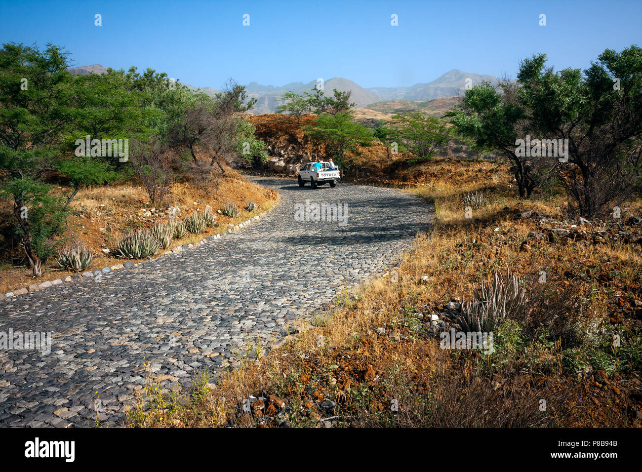 SANTO ANTAO, CAPE VERDE - DECEMBER 08, 2015: Winding stone road among hills. Tourists explore the Santo Antao island   landscape in Toyota truck. Stock Photo