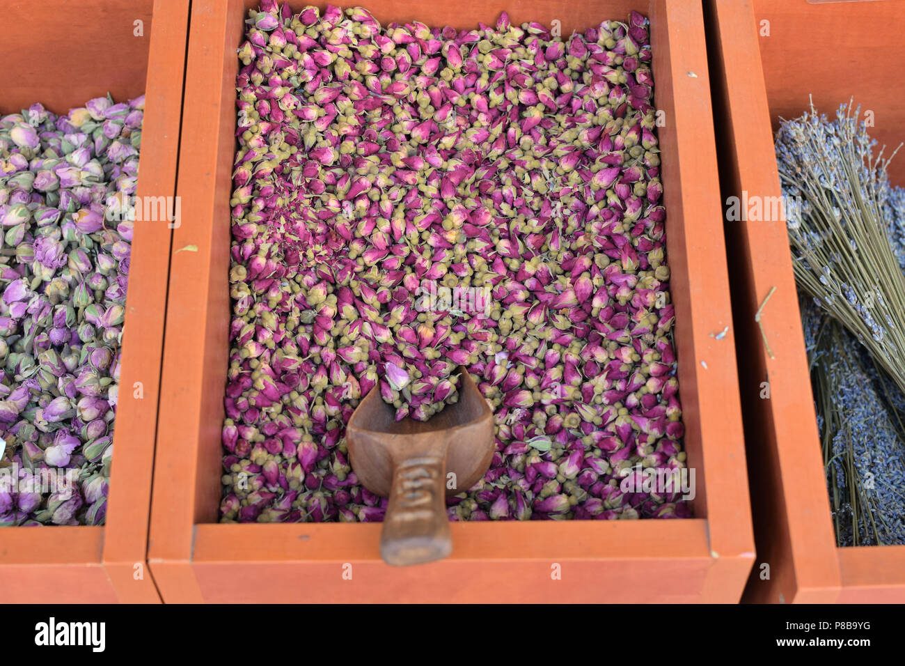 Dried red roses aromatic rosebuds and other spices for sale in wooden crates. Stock Photo