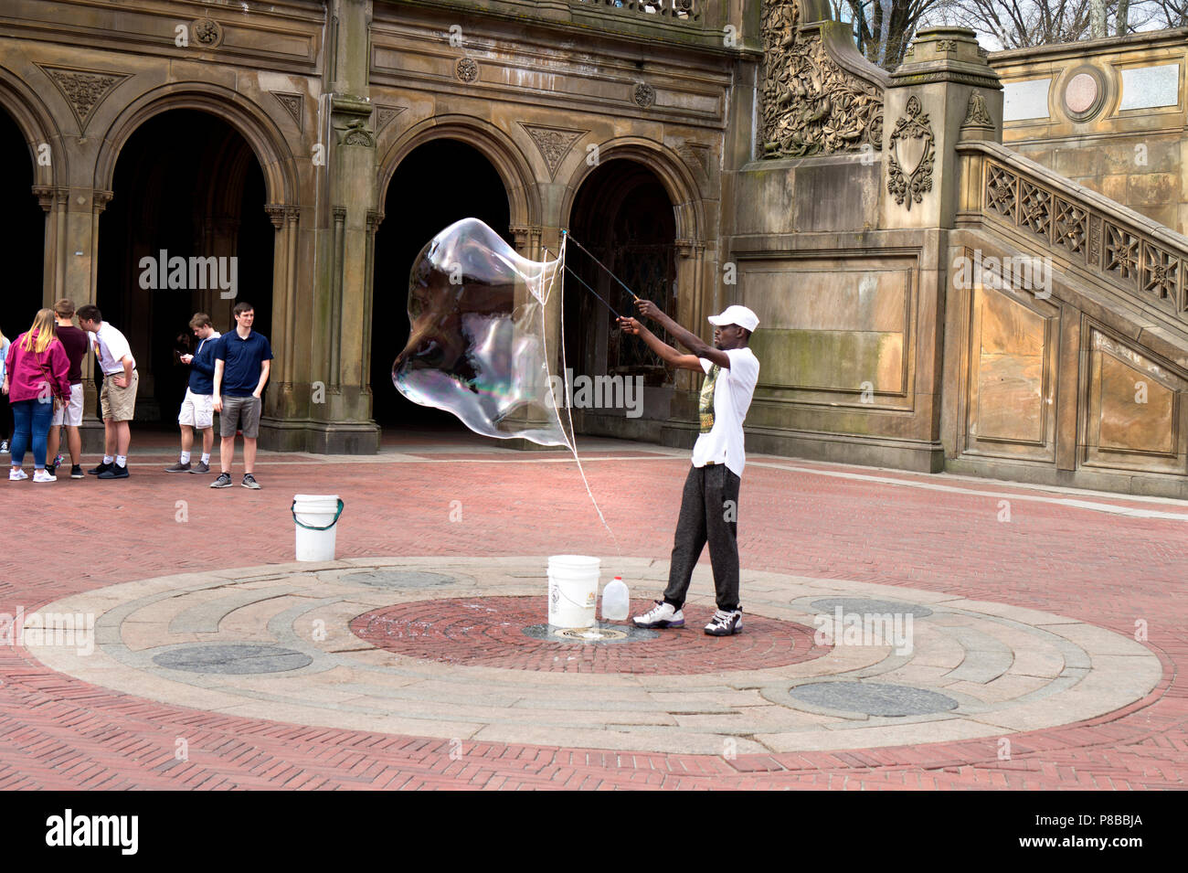 New York, NY / USA - 04.13.2018: Afro american man making a big soap bubble with bubble wand in the Central Park in NYC Stock Photo