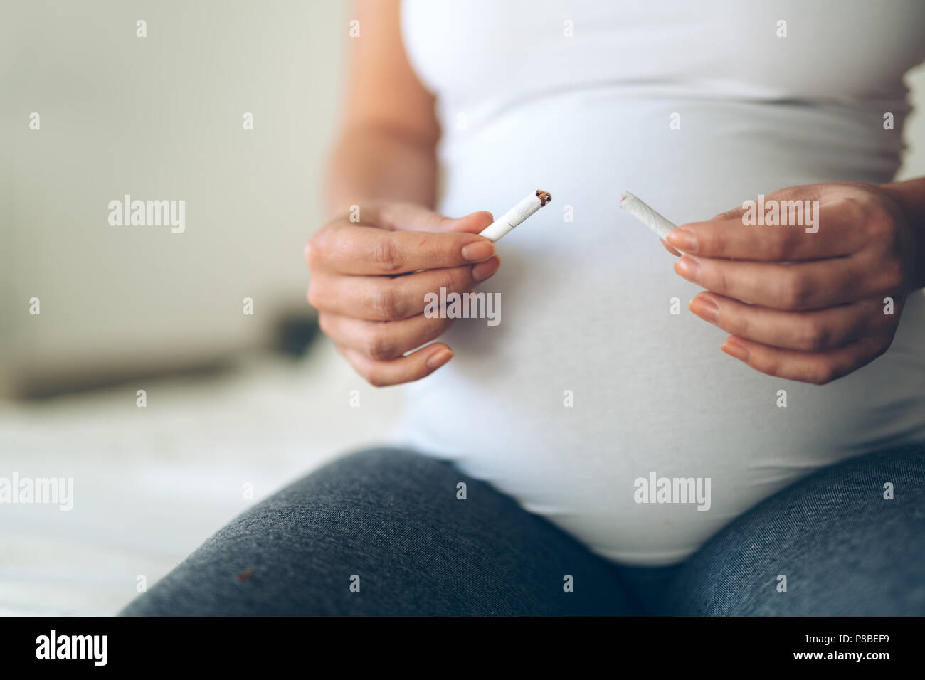 Health minded pregnant woman breaks last cigarette Stock Photo