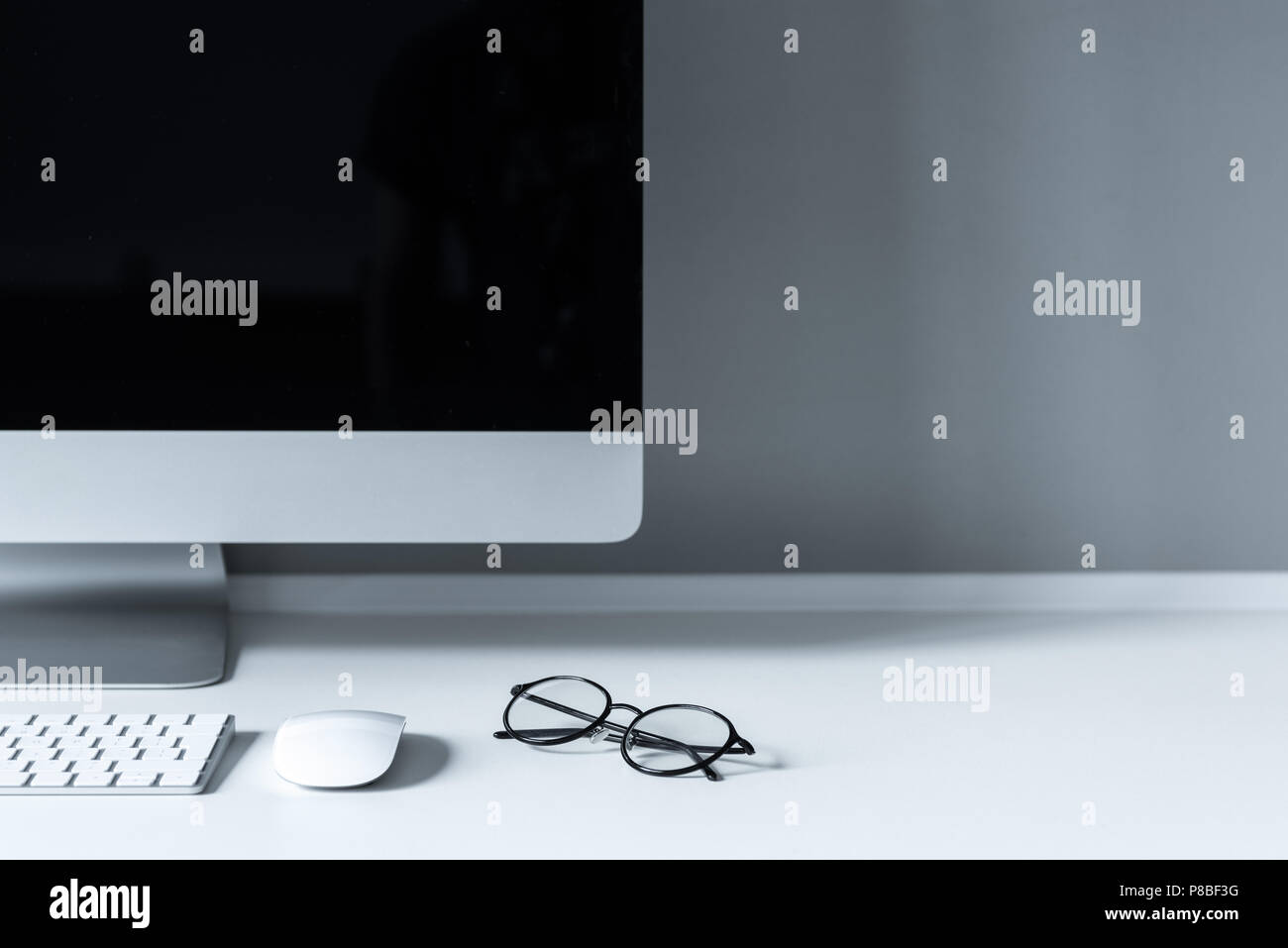 glasses and computer mouse with keyboard on working table Stock Photo