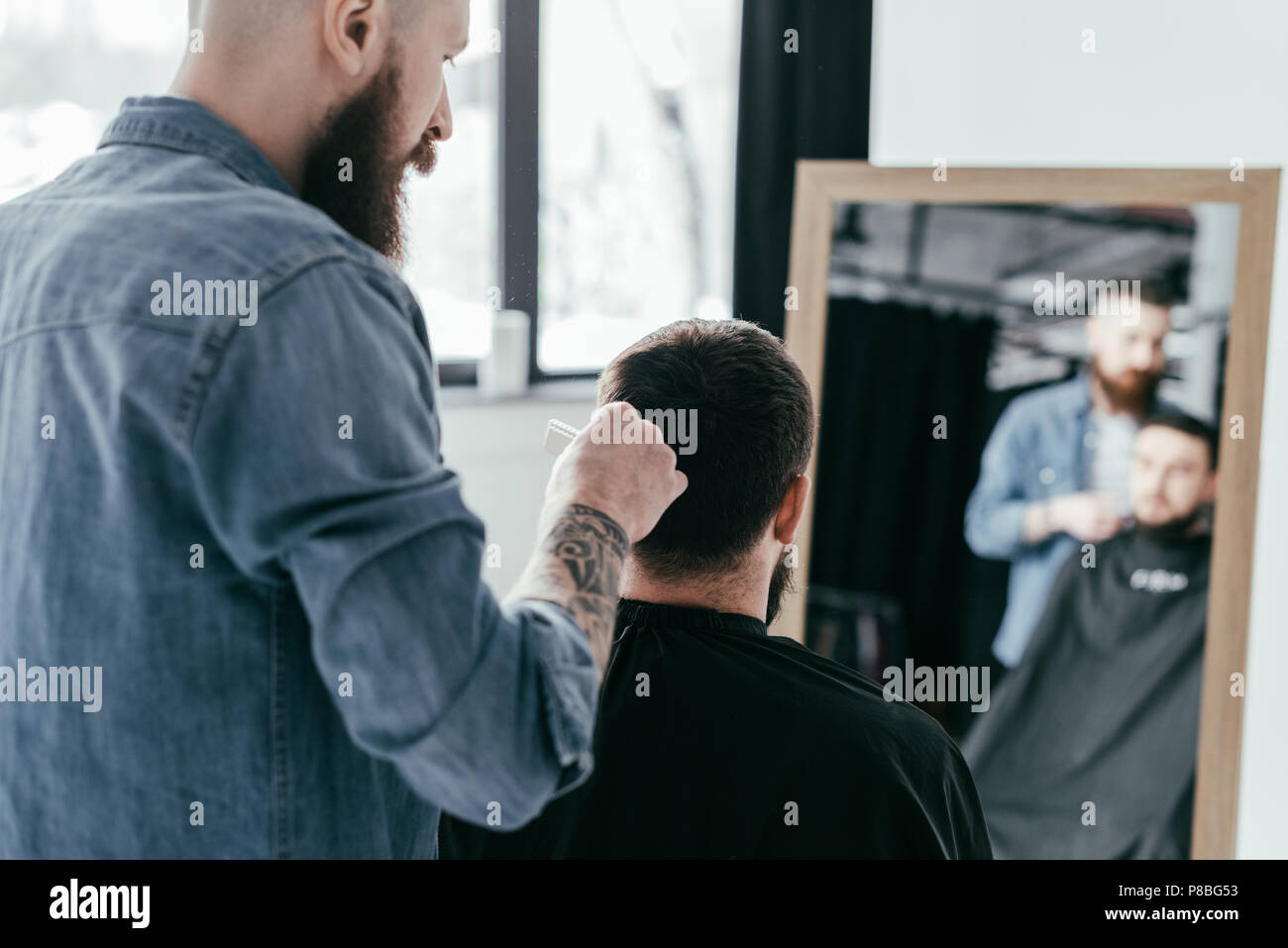 rear view of barber combing customer hair at barbershop Stock Photo