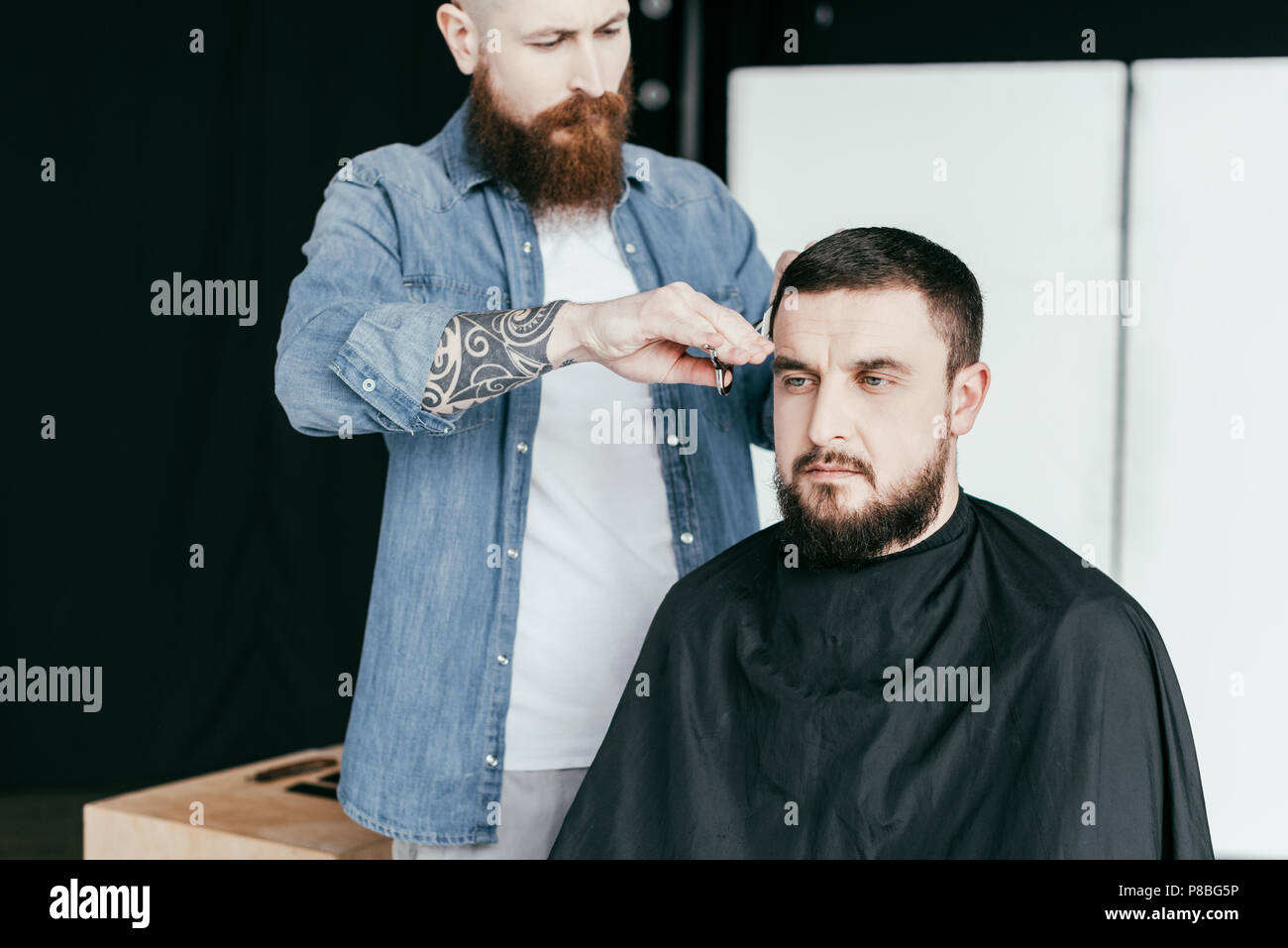 barber cutting serious customer hair at barbershop Stock Photo