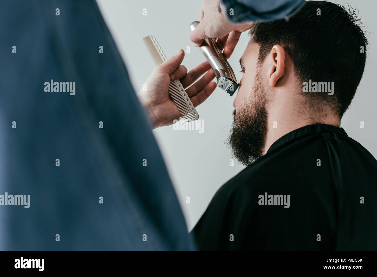 cropped image of barber trimming customer beard at barbershop Stock Photo