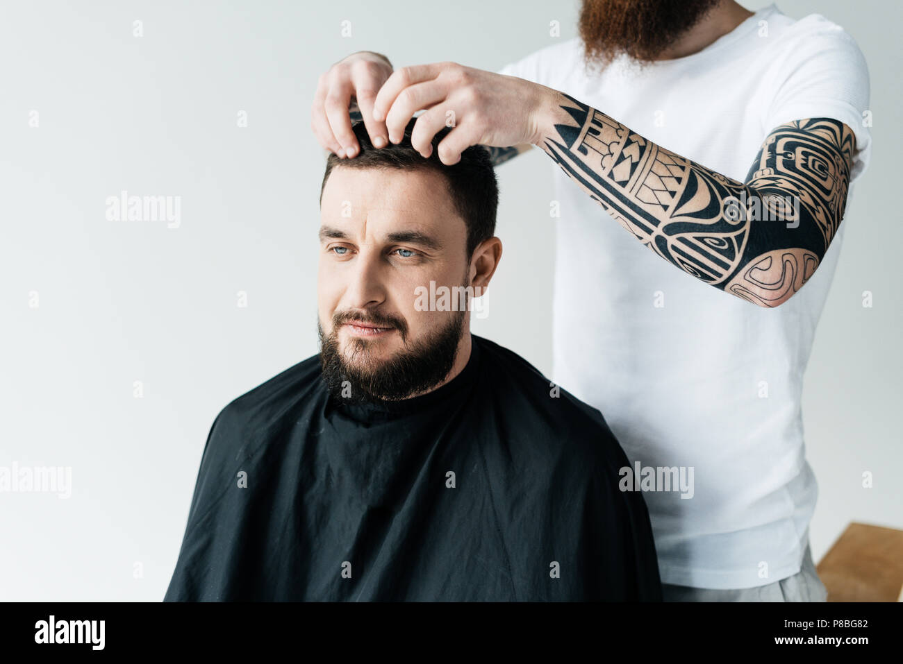 cropped image of barber styling customer hair at barbershop isolated on white Stock Photo