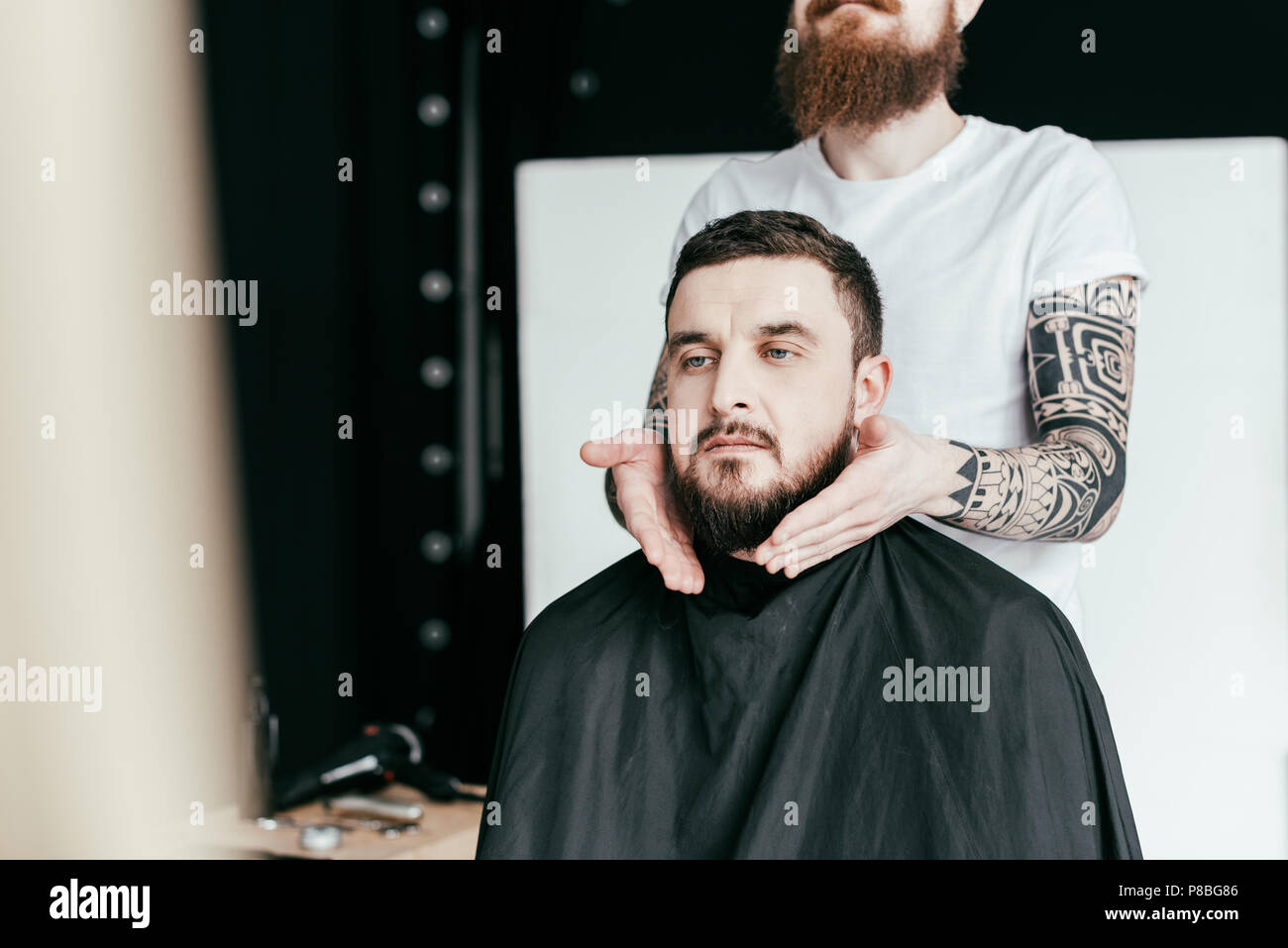 cropped image of barber styling customer beard at barbershop Stock Photo