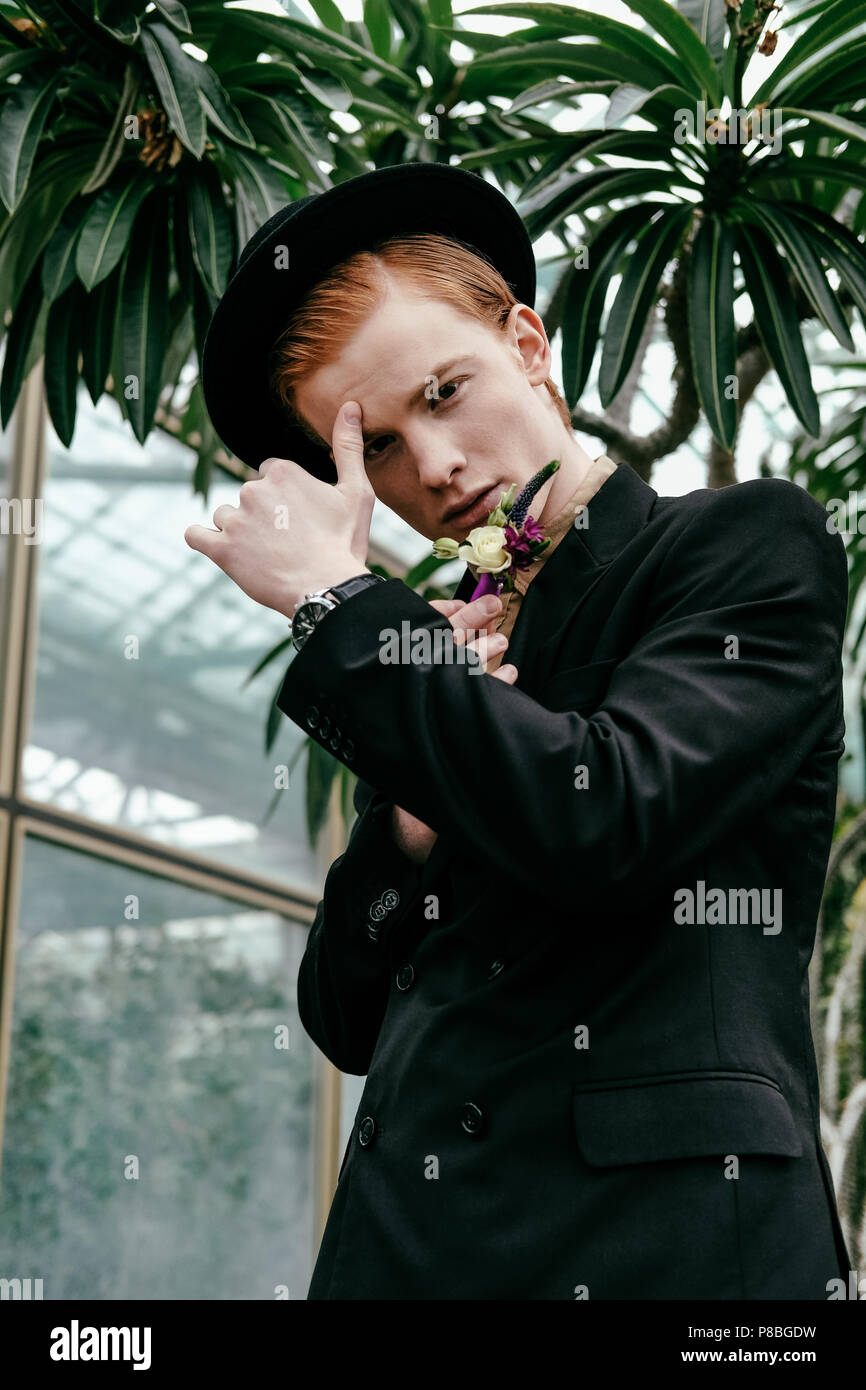 portrait of stylish young red hair man in hat in glasshouse Stock Photo