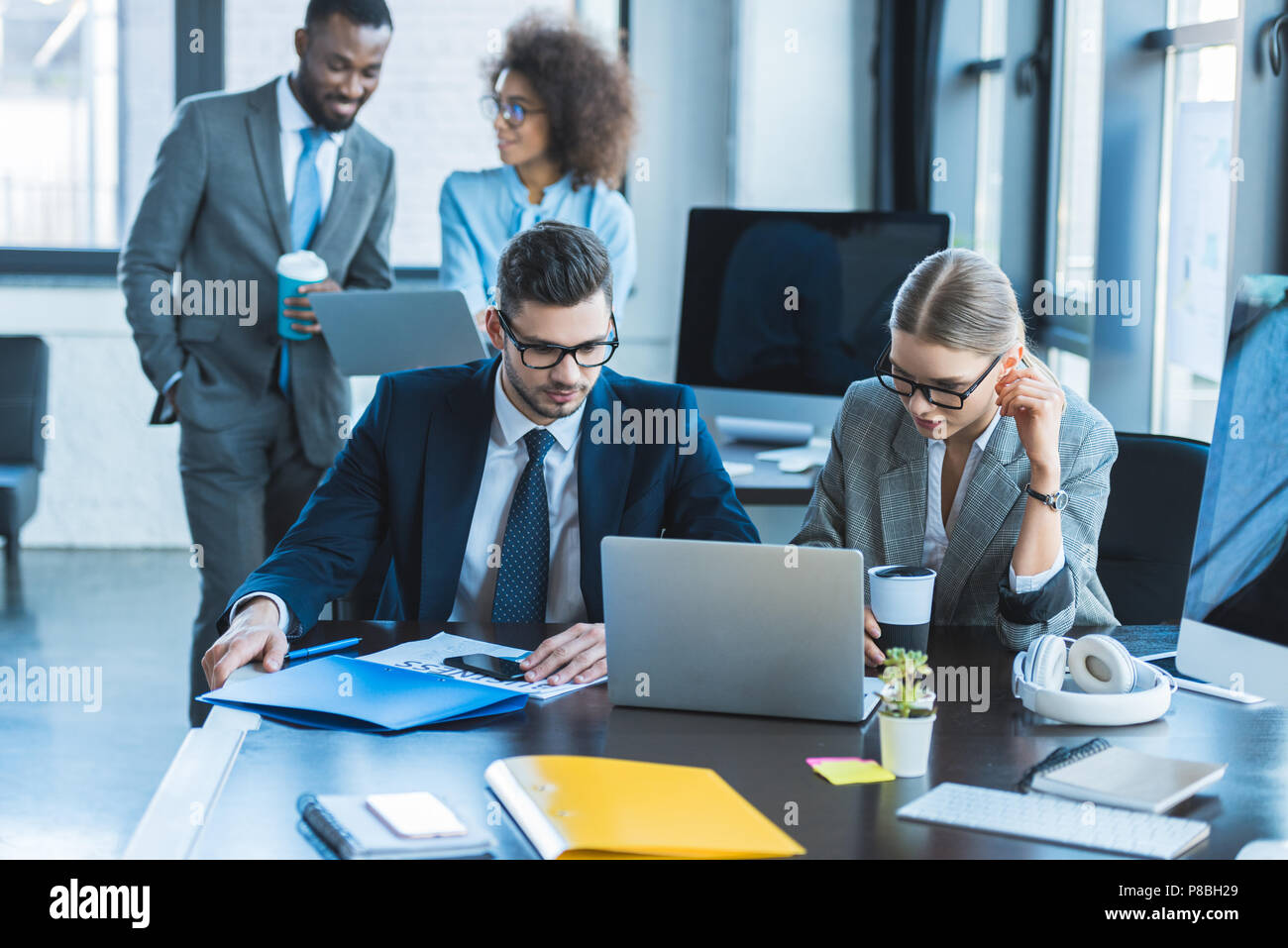 multicultural businesspeople looking at laptops in office Stock Photo