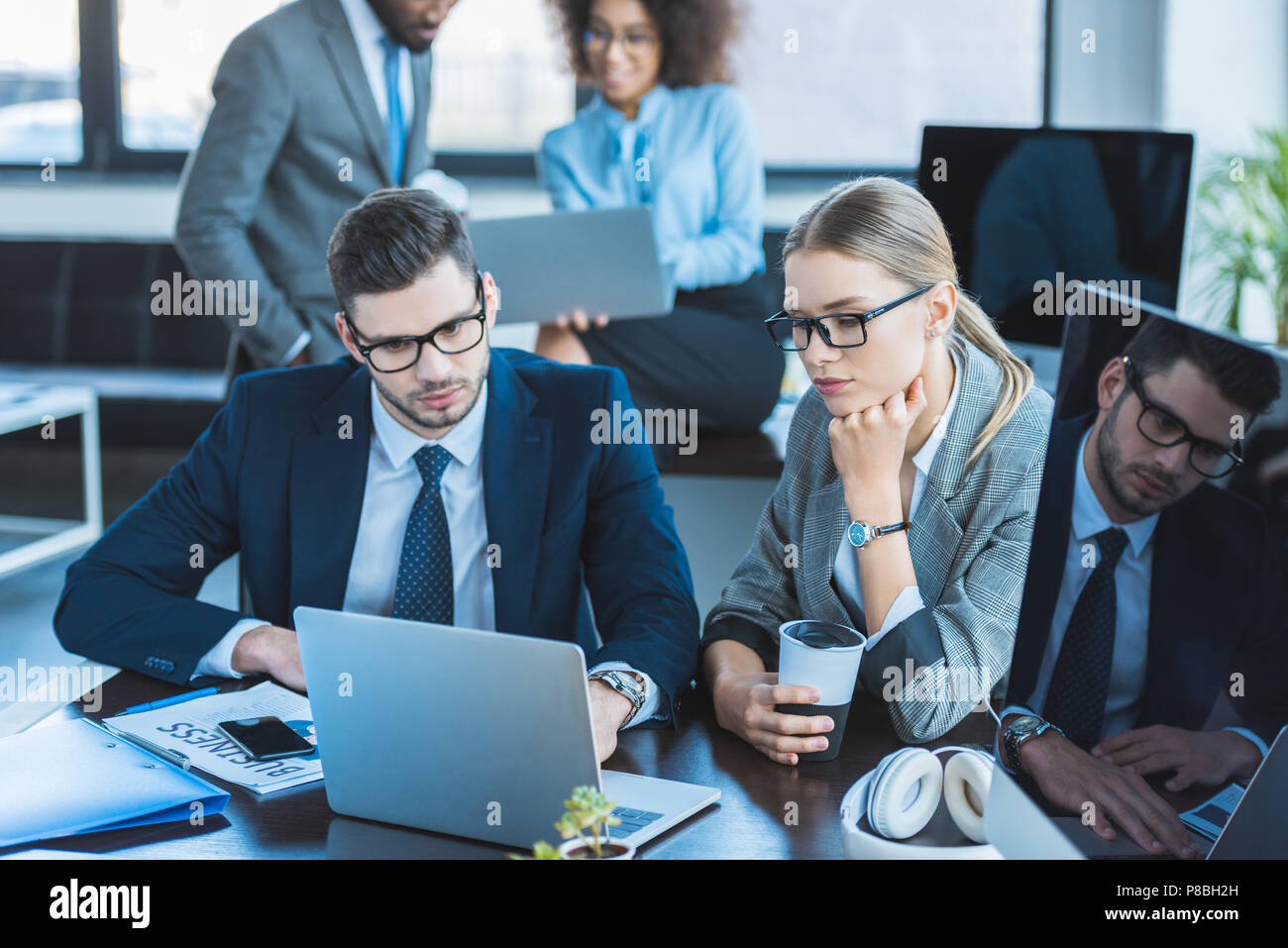 multicultural businesspeople looking at laptops in workspace Stock Photo
