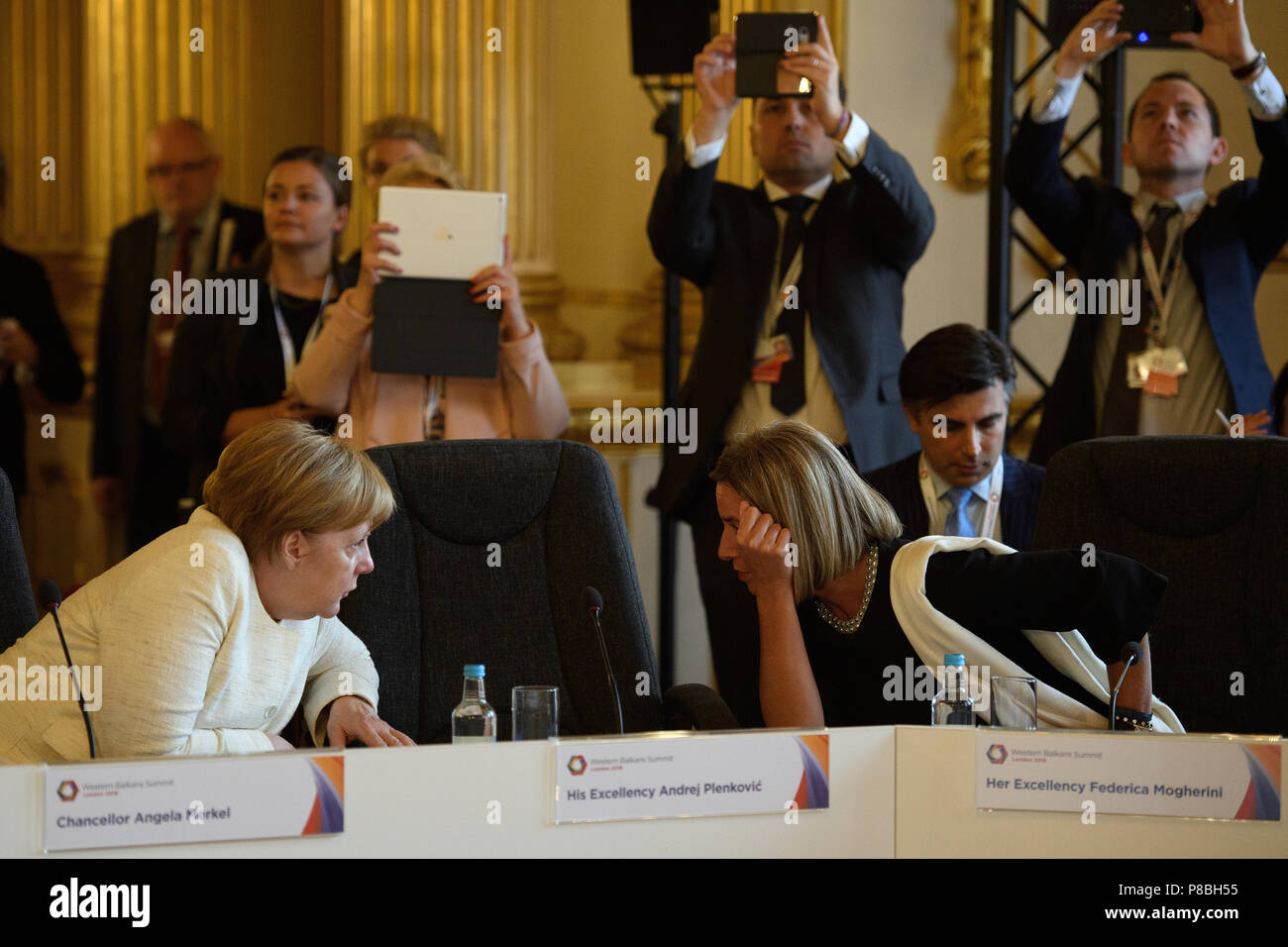 Germany's Chancellor Angela Merkel and Vice-President of the EU Commission Federica Mogherini speak as they attend a plenary session during the second day of Western Balkans summit at Lancaster House, London. Stock Photo