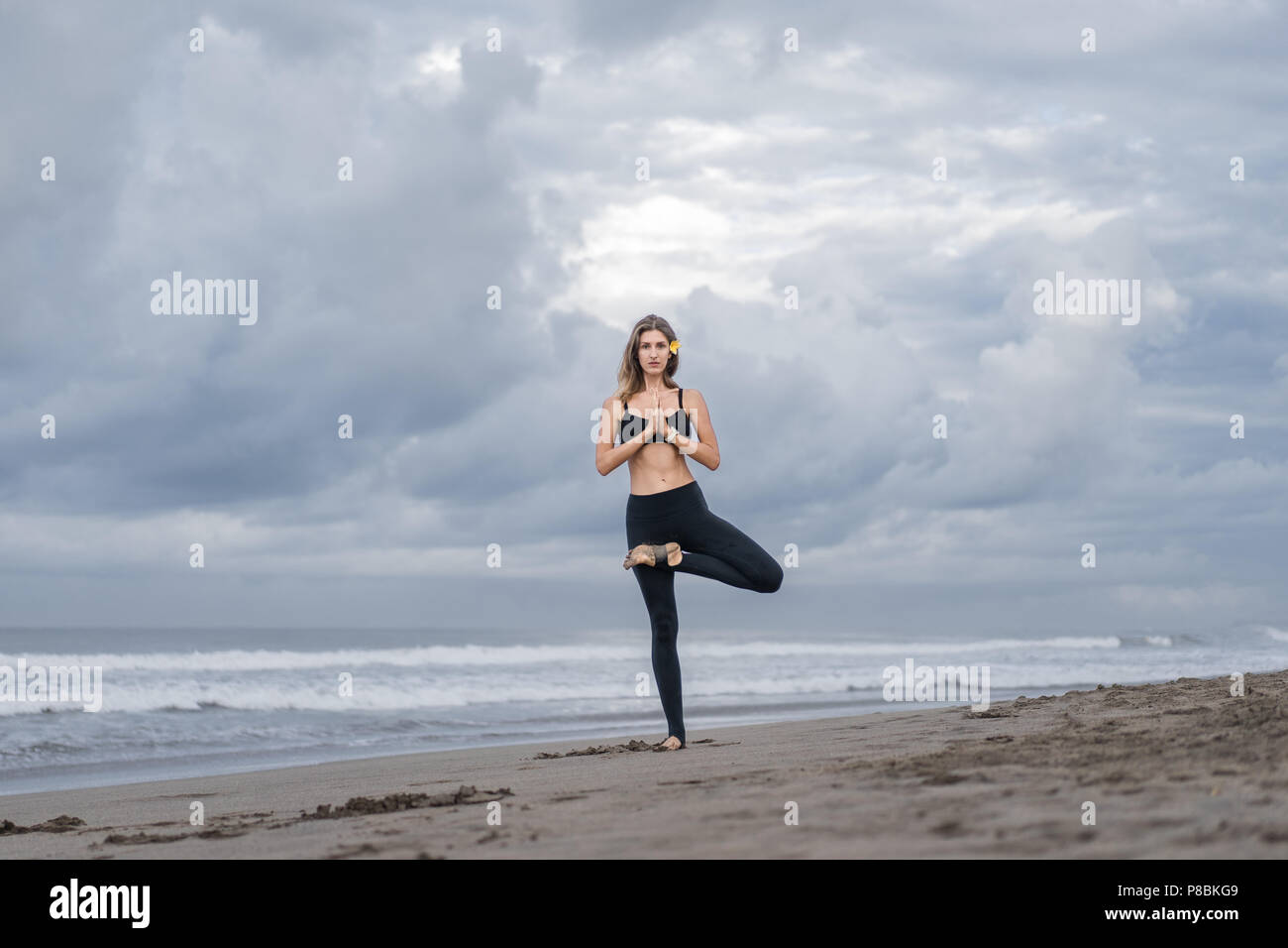 attractive young woman practicing yoga in Tree pose (Vrksasana) on ...