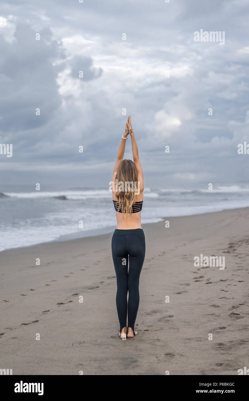 rear view of young woman practicing yoga in Mountain pose (Tadasana) on ...
