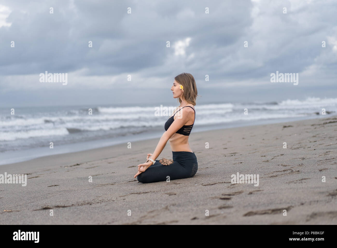 young woman practicing yoga in lotus pose on seashore Stock Photo - Alamy