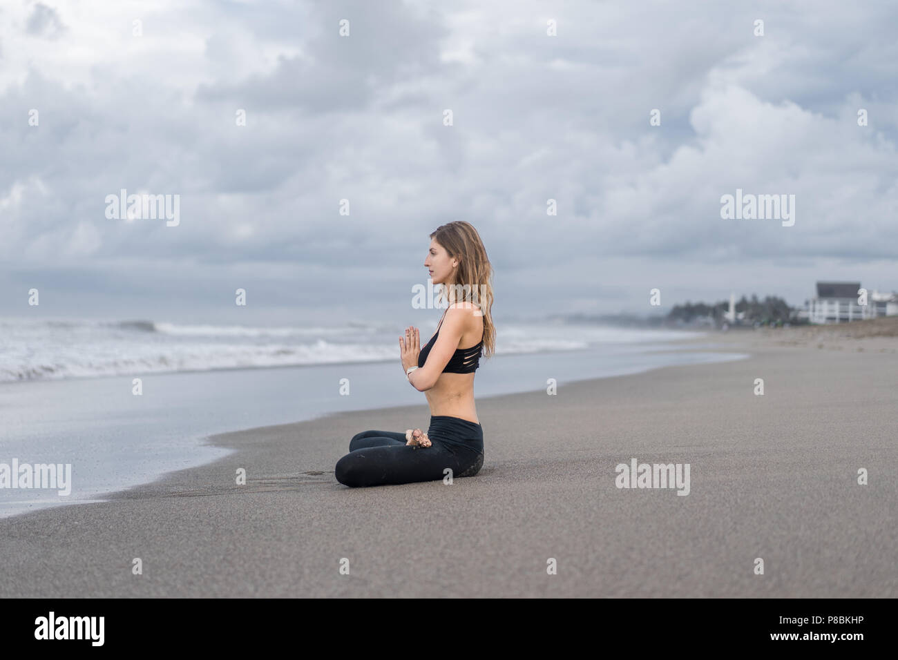 side view of beautiful young woman practicing yoga in lotus pose ...