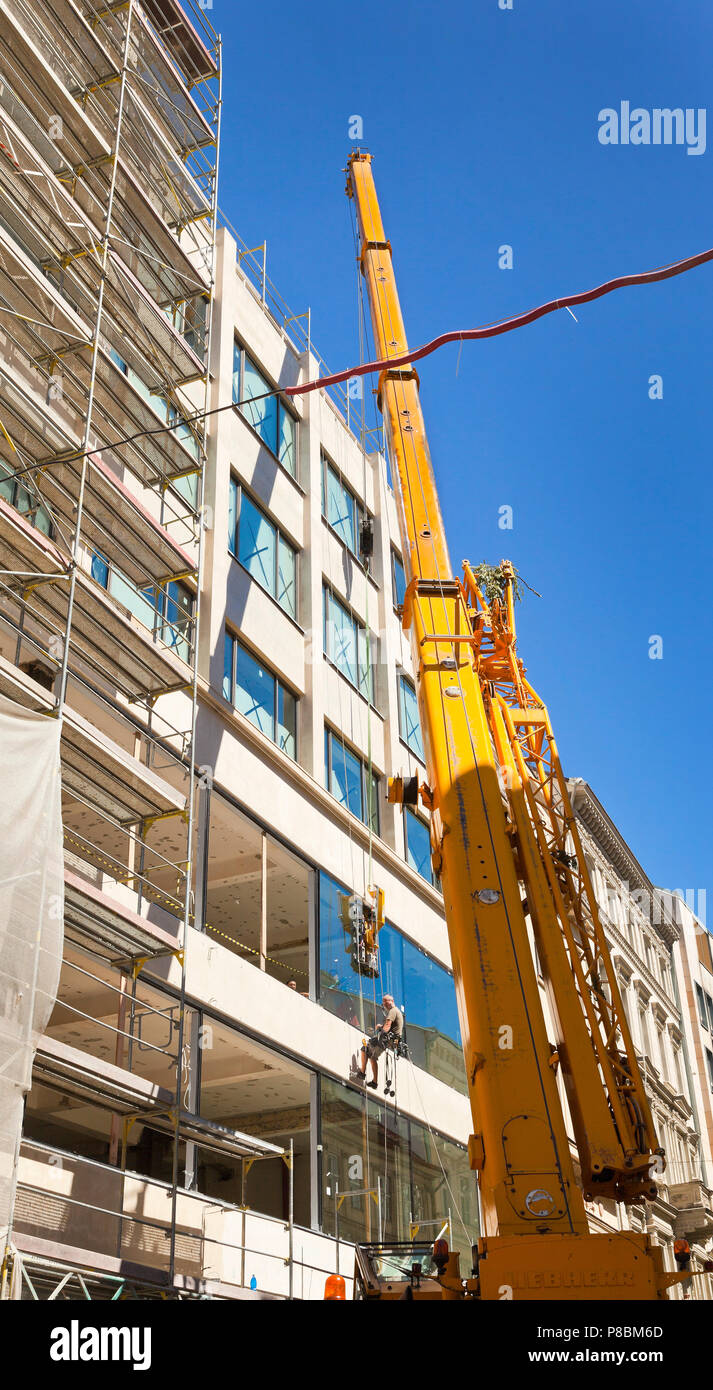 Building contactors installing large glass panels in a building aperture Stock Photo