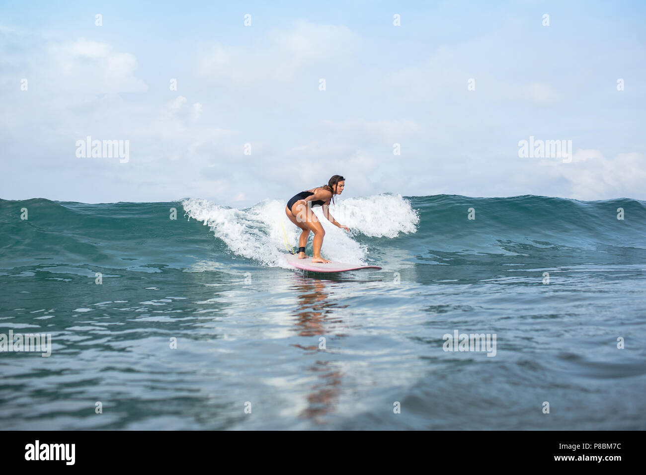 attractive young woman riding on wave on surfboard in ocean Stock Photo ...
