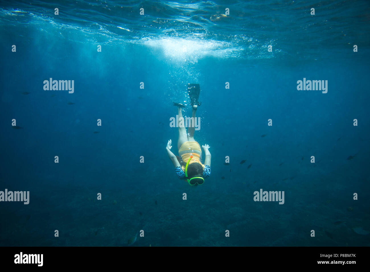 underwater photo of woman in fins, diving mask and snorkel diving alone