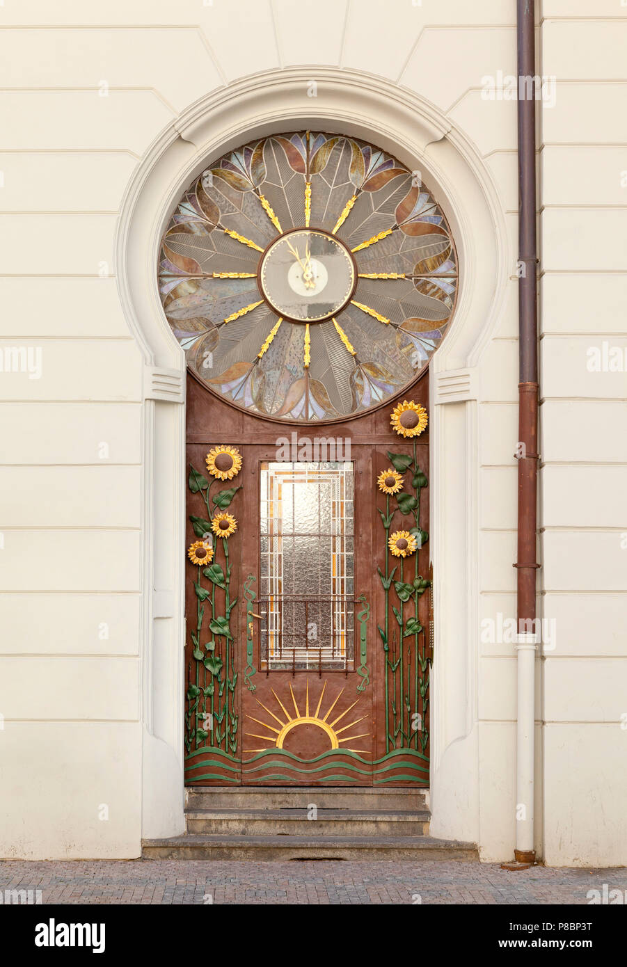 Ornate artistic entrance door with sunflower and sun design motifs clock face Stock Photo