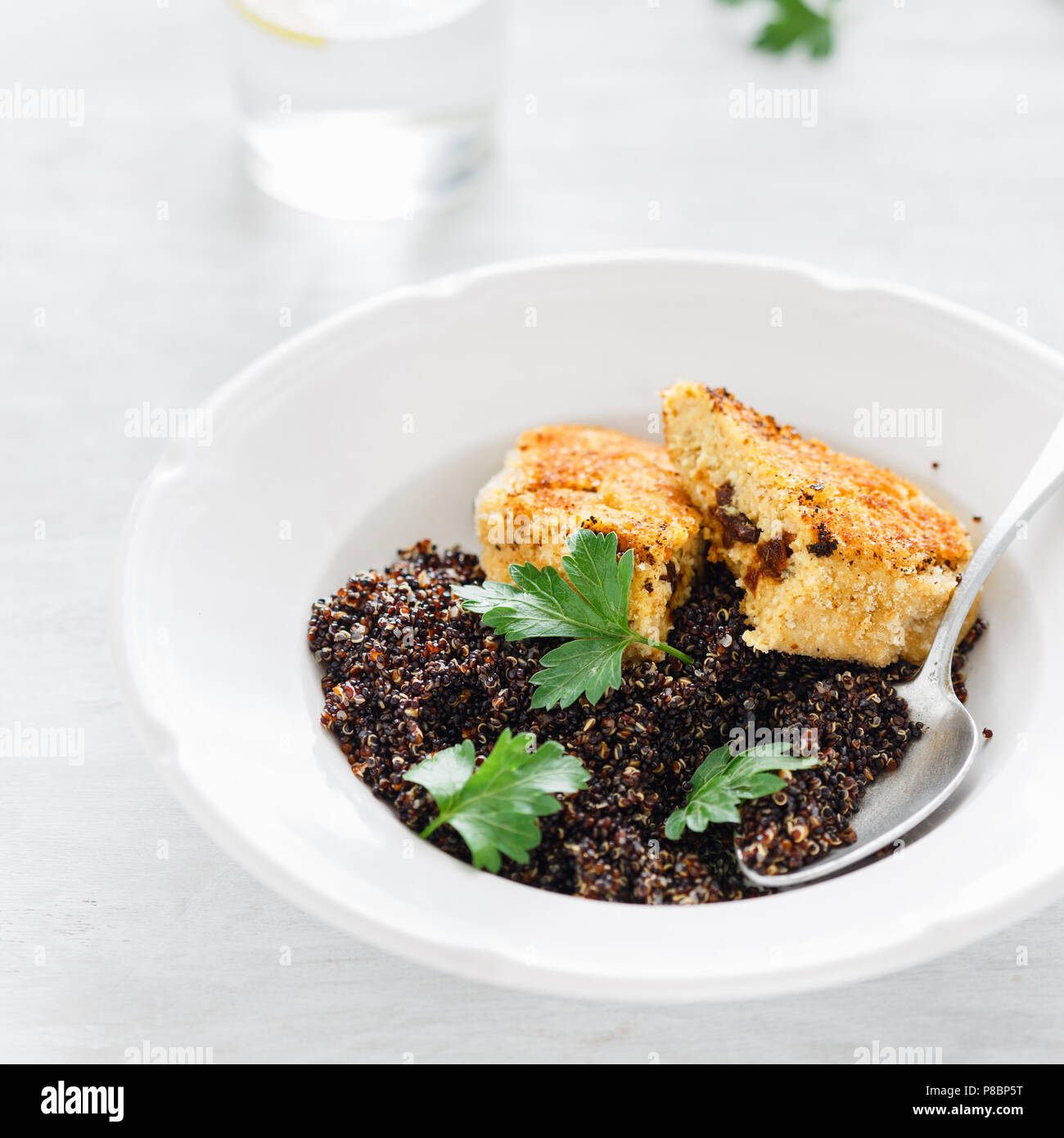Vegetarian dinner table. Close up plate with black quinoa and oatmeal cutlets with prunes on white wooden table Stock Photo