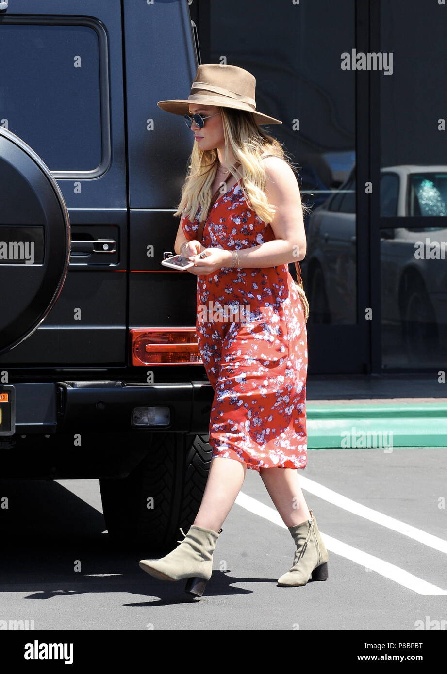 Pregnant Hilary Duff conceals her baby bump in a red summer dress as