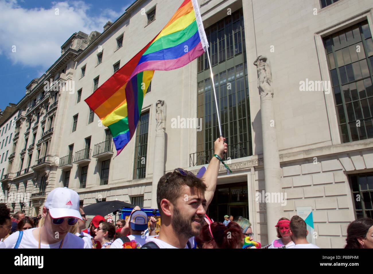A man holding a rainbow flag in the air in the Pride in London 2018 Parade Stock Photo