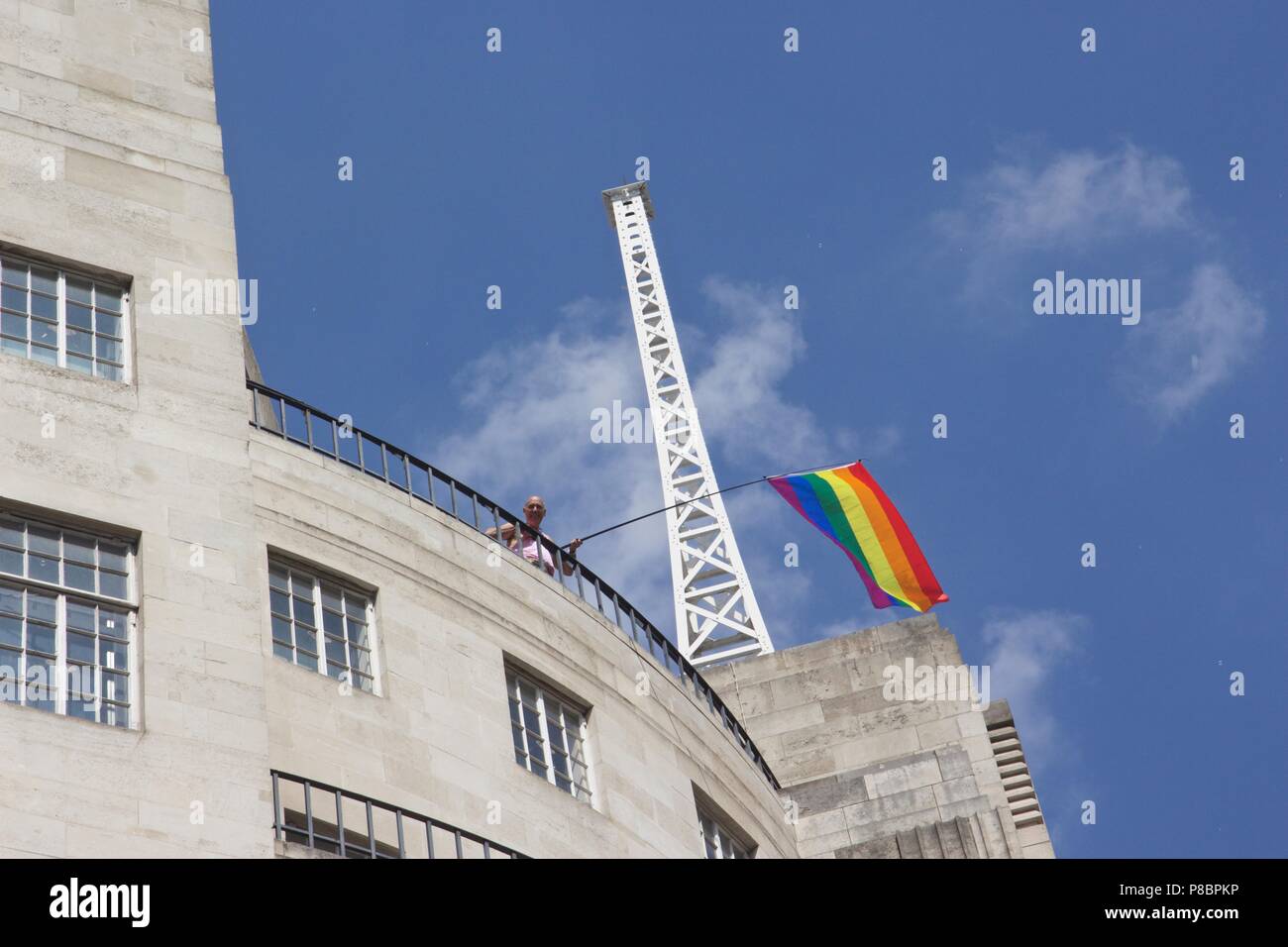 A man on top of BBC broadcasting house waving a rainbow flag at Pride in London 2018 Stock Photo
