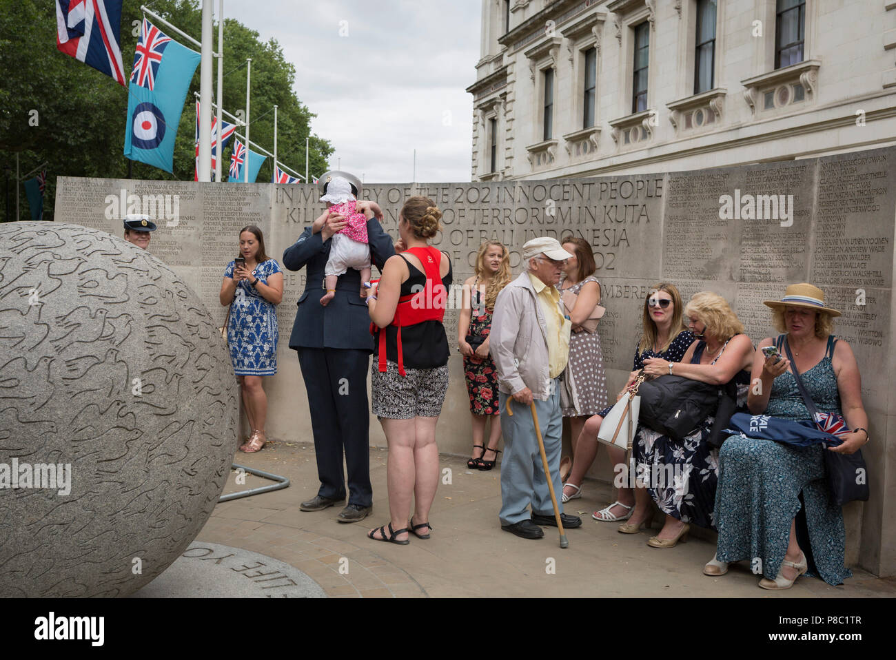 On the 100th anniversary of the Royal Air Force (RAF) and following a flypast of 100 aircraft formations representing Britain's air defence history which flew over central London, a serviceman holds his child next to the memorial to those killed in the 2002 Bali bombing, on 10th July 2018, in London, England. (Photo by Richard Baker / In Pictures via Getty Images) Stock Photo