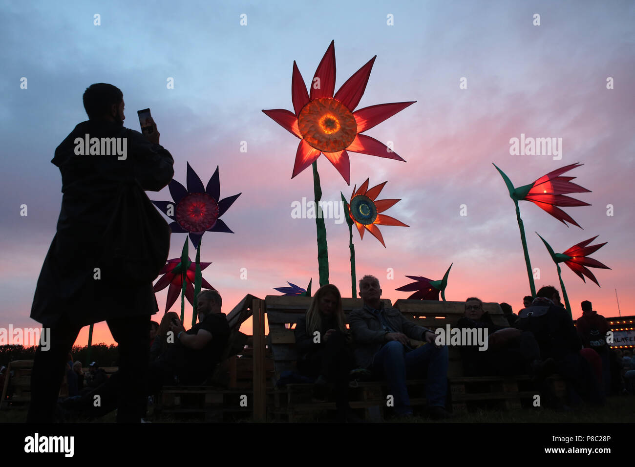 Hoppegarten, Germany, woman takes a photo of bright artificial flowers in the evening at Lollapalooza Berlin 2017 at the Hoppegarten racecourse Stock Photo