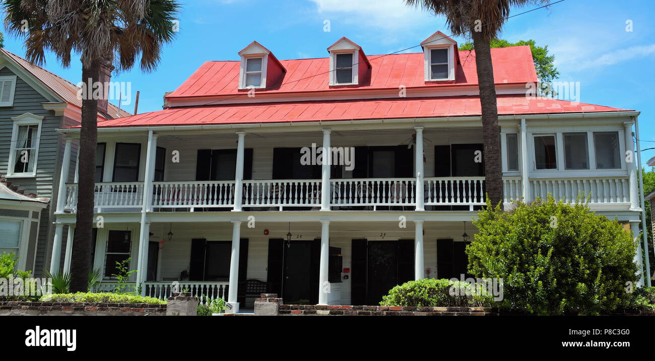 Nineteenth Century Home with Red Tin Roof, two Levels and Verandas FAcing Two Palmetto Trees Stock Photo
