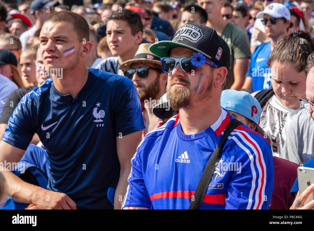 French football supporters cheering on the national team during the World Cup while watching the game on a huge public television screen Stock Photo