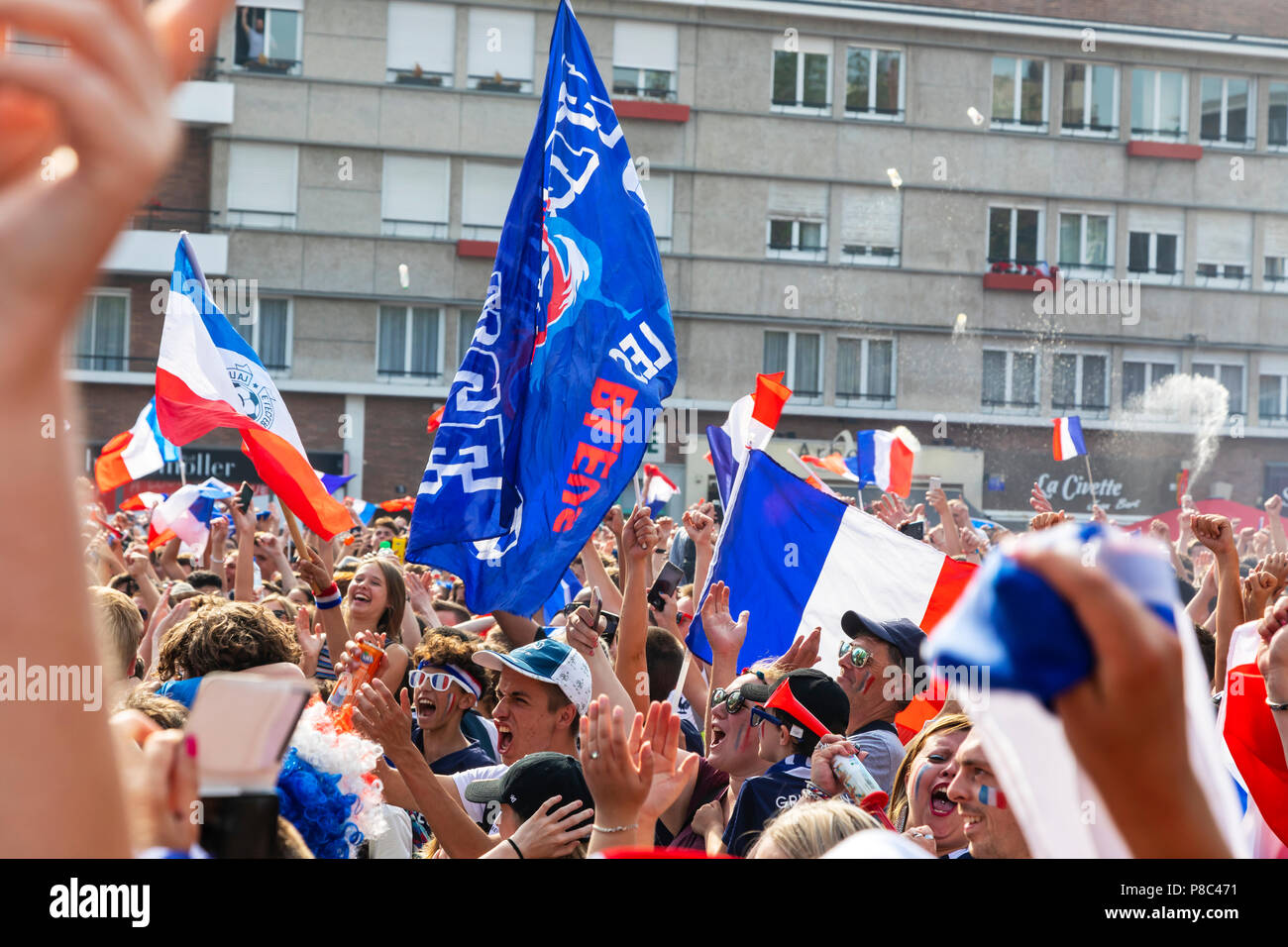 French football supporters cheering on the national team during the World Cup while watching the game on a huge public television screen Stock Photo