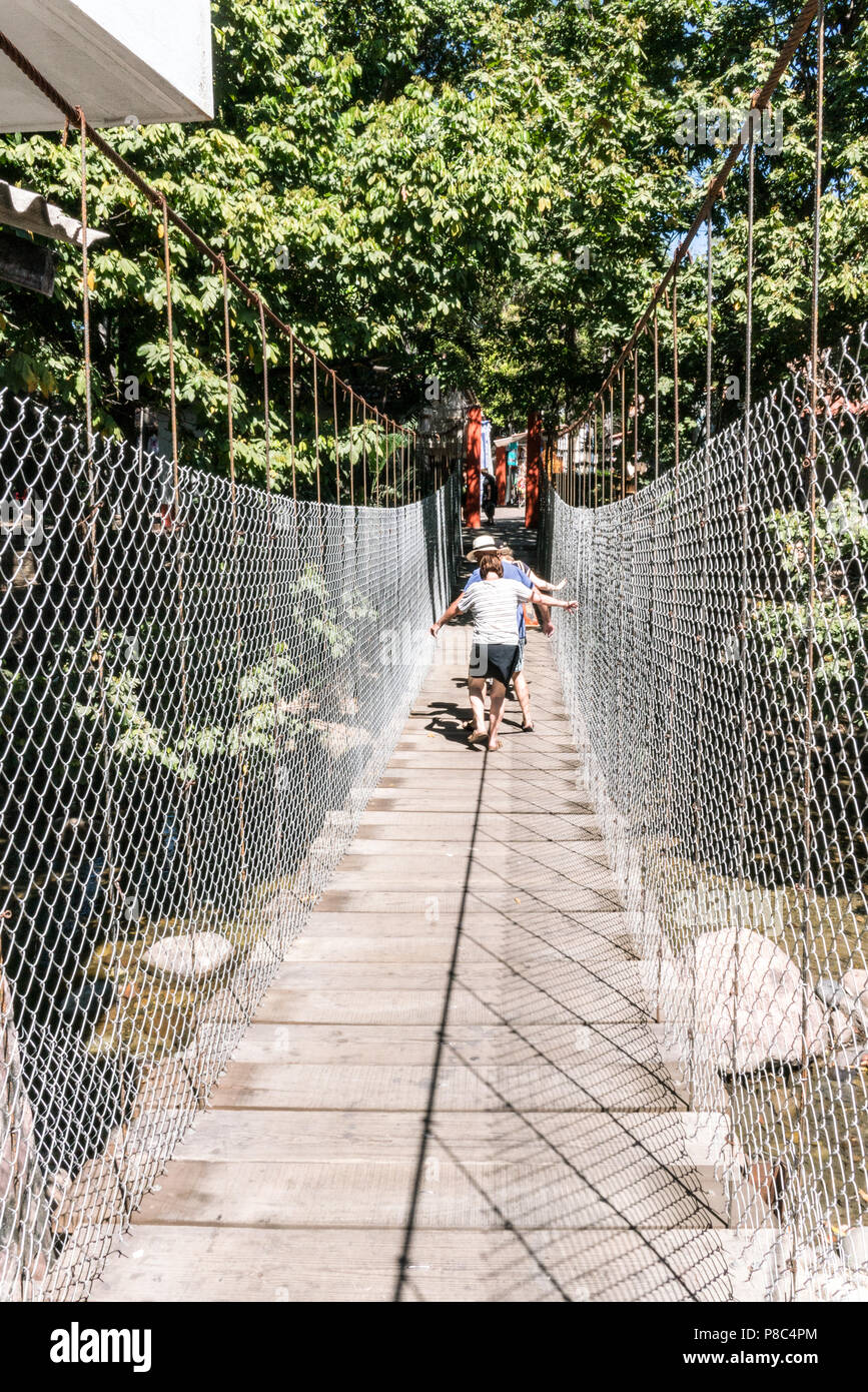 PUERTO VALLARTA, MEXICO - March 10 2018: Tourists walking along the unstable suspension bridge to Isla Rio Cuale from downtown Puerto Vallarta, MX-JAL Stock Photo