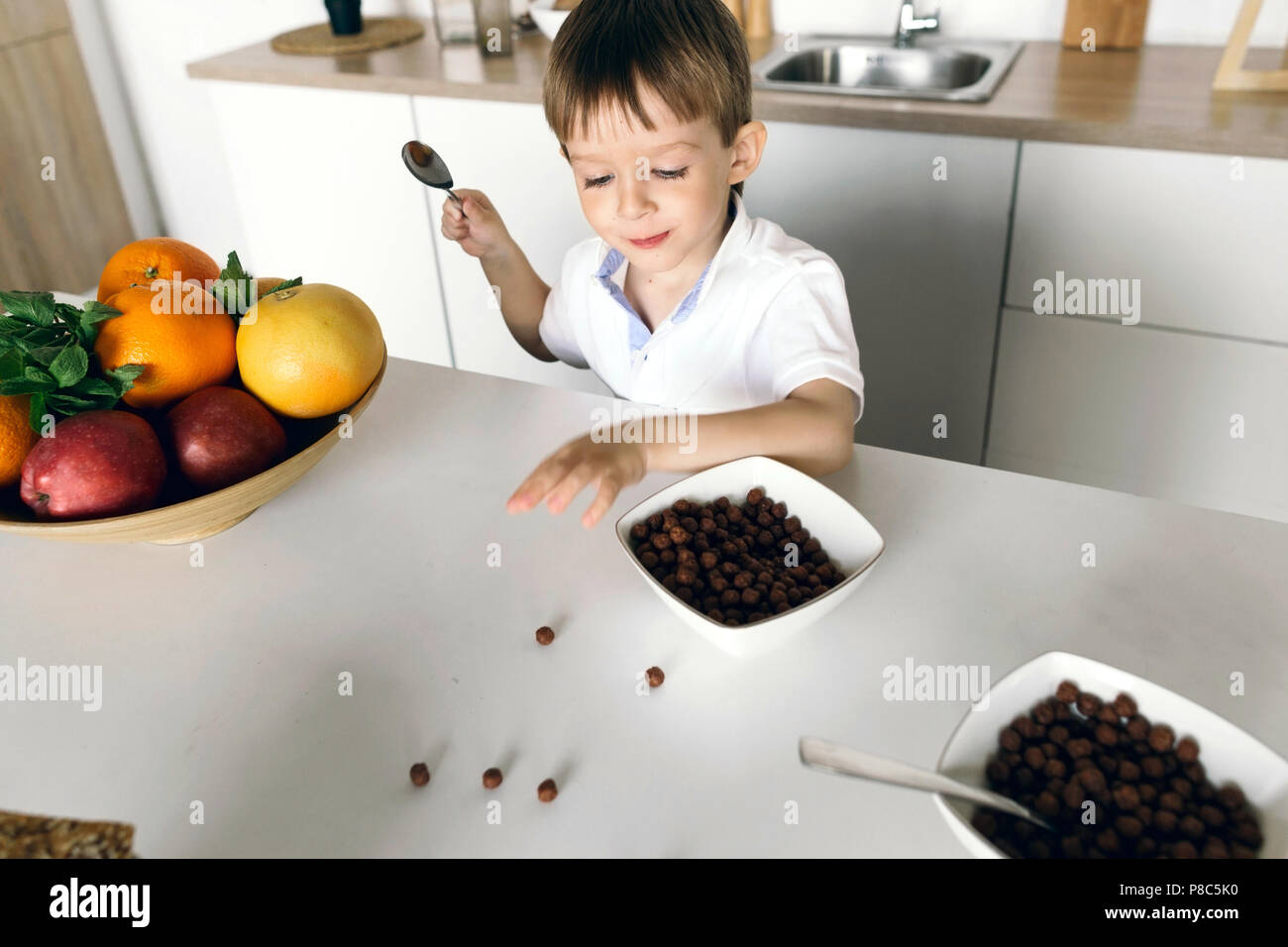 Cute little boy eating dry breakfast at home in the kitchen Stock Photo