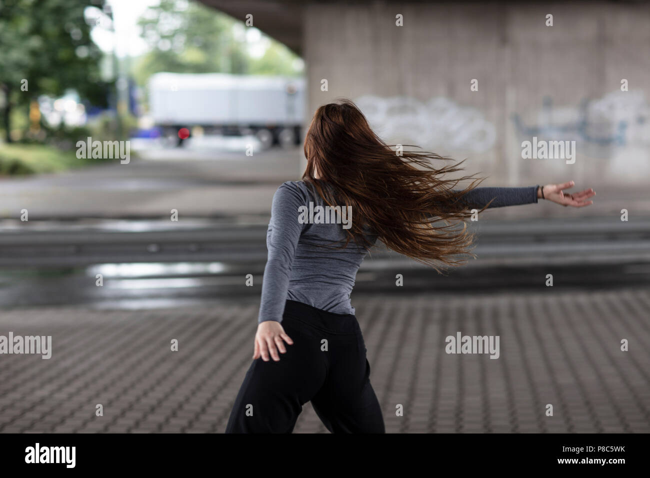 Rear view of a female street dancer in motion performing on a paved ...