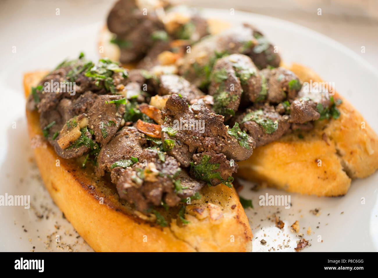 Chicken livers bought from a supermarket that have been fried with garlic and parsely and served on white bread that has been fried in butter, garlic  Stock Photo