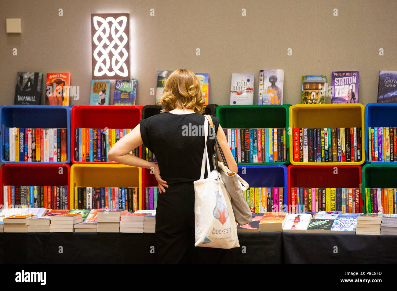 A woman browses a selection of colourful modern children's books. Stock Photo
