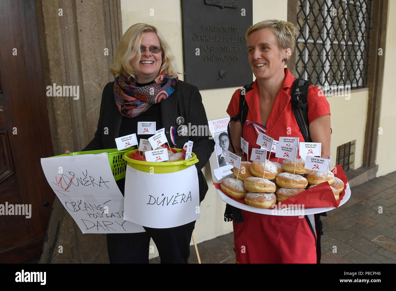 Prague, Czech Republic. 11th July, 2018. Protesters against Babis's government gives donuts with the hammer and sickle communist symbol in front of a Chamber of Deputies of the Czech Republic building in Prague, Czech Republic, on July 11, 2018, prior to the Chamber of Deputies session on confidence in minority government of ANO and CSSD. Government supporters PM's got a donut with the communist symbol and opponents PM's got a Czech tricolor. Credit: Michal Krumphanzl/CTK Photo/Alamy Live News Stock Photo