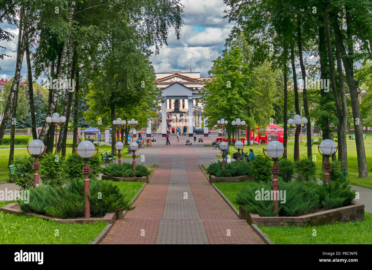 leading to a high arched gateway in a park with benches with a resting people . For your design Stock Photo