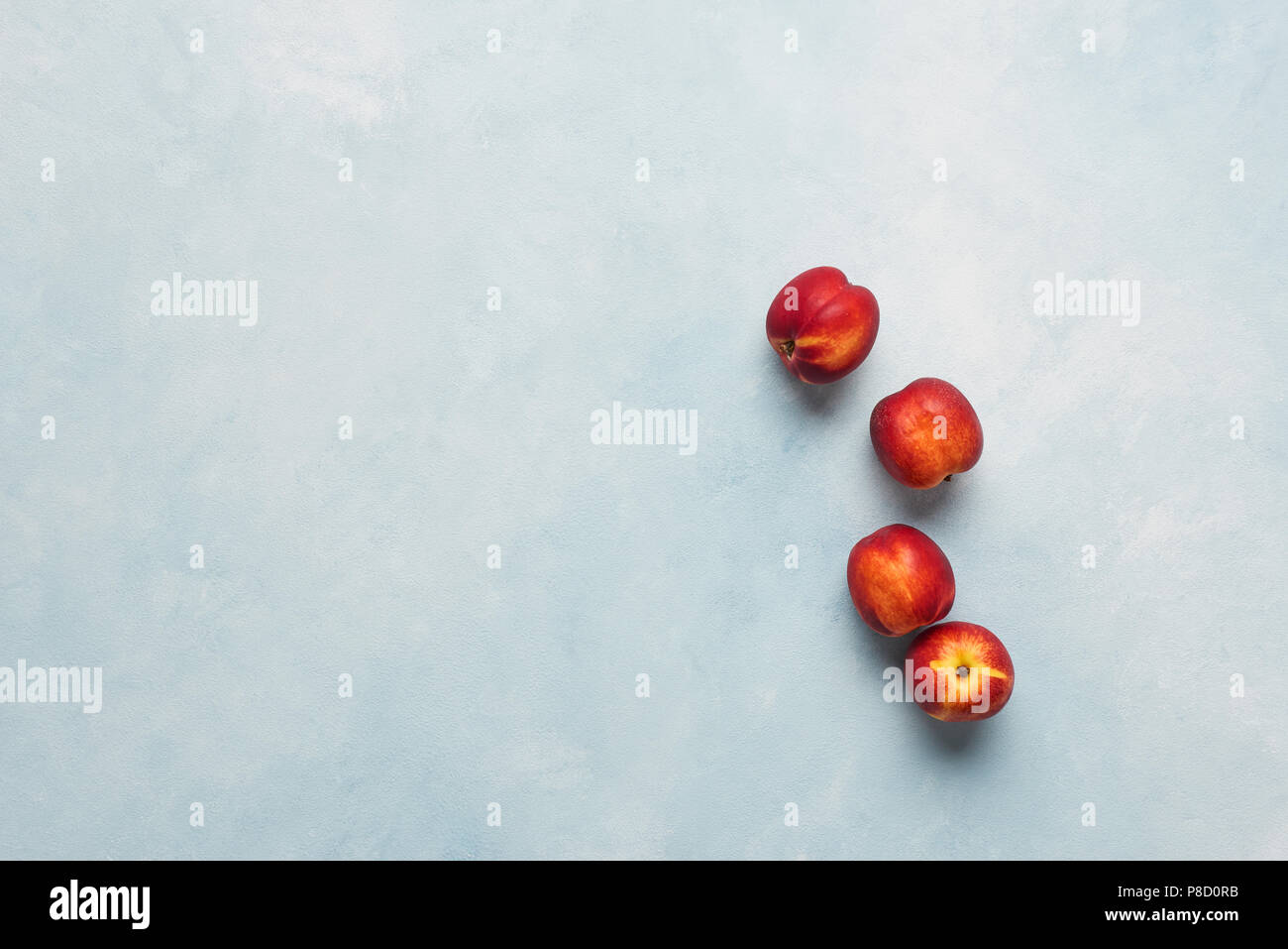 Flat lay of fresh nectarines fruits on light blue background. Top view with copy space. Stock Photo