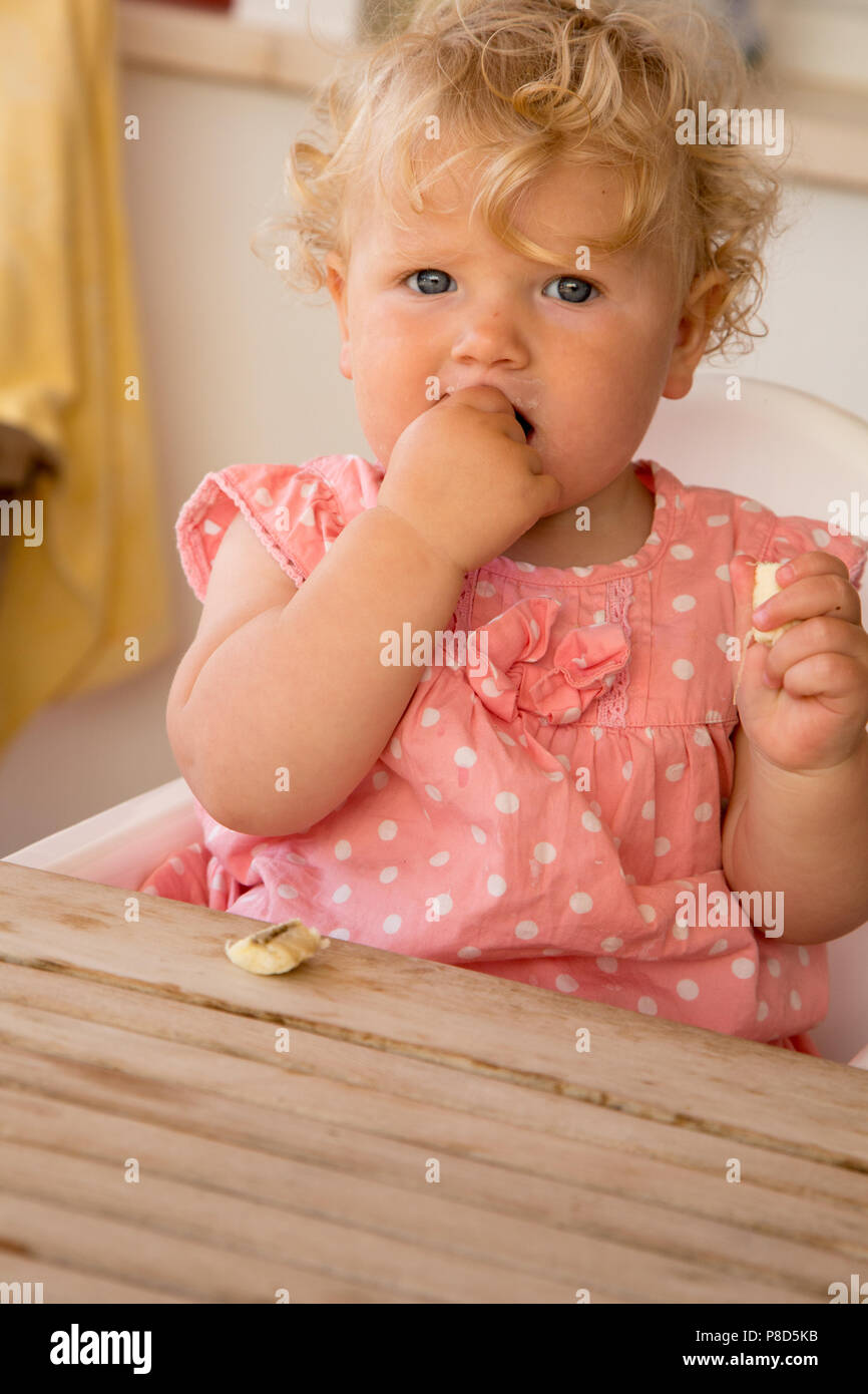 A One Year Old Girl Feeding Herself A Banana Stock Photo Alamy