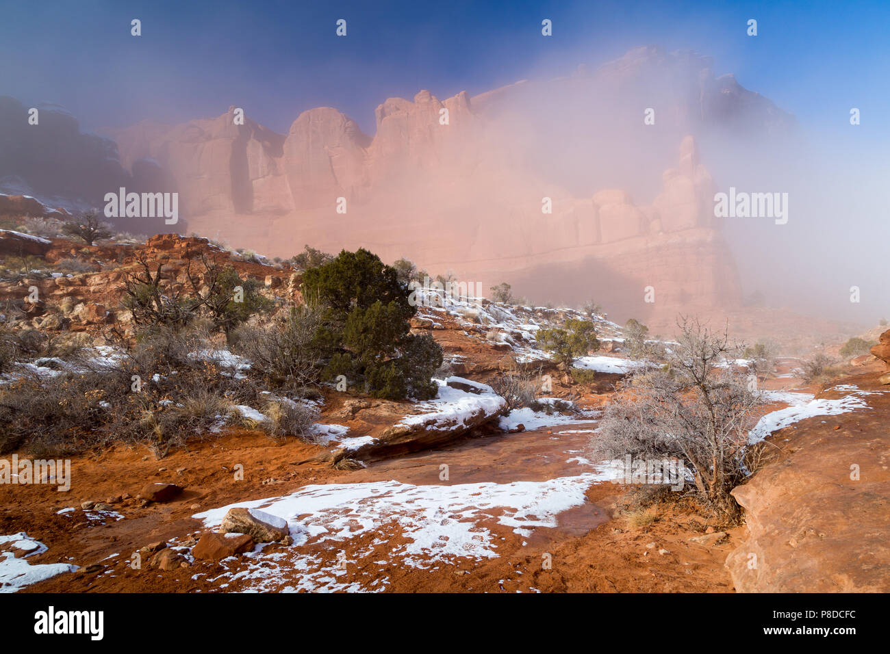 A thick winter fog clearing off of large sandstone buttes above melting