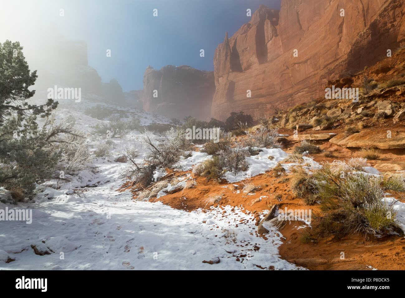 A snow-covered wash descending out from large sandstone buttes along the Park Avenue Trail. Arches National Park, Utah Stock Photo