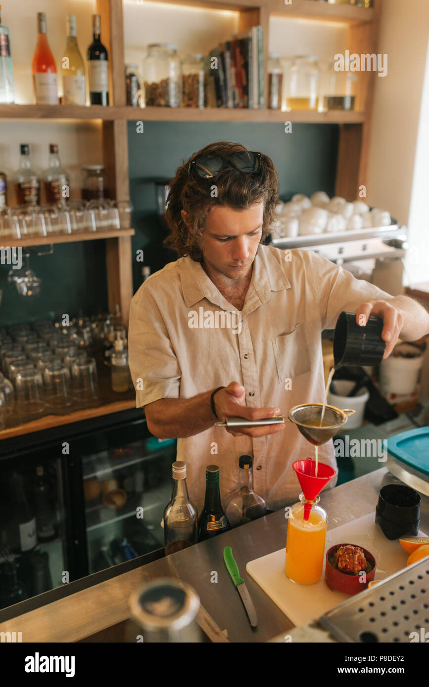 Young male bartender mixing cocktails behind a bar counter Stock Photo