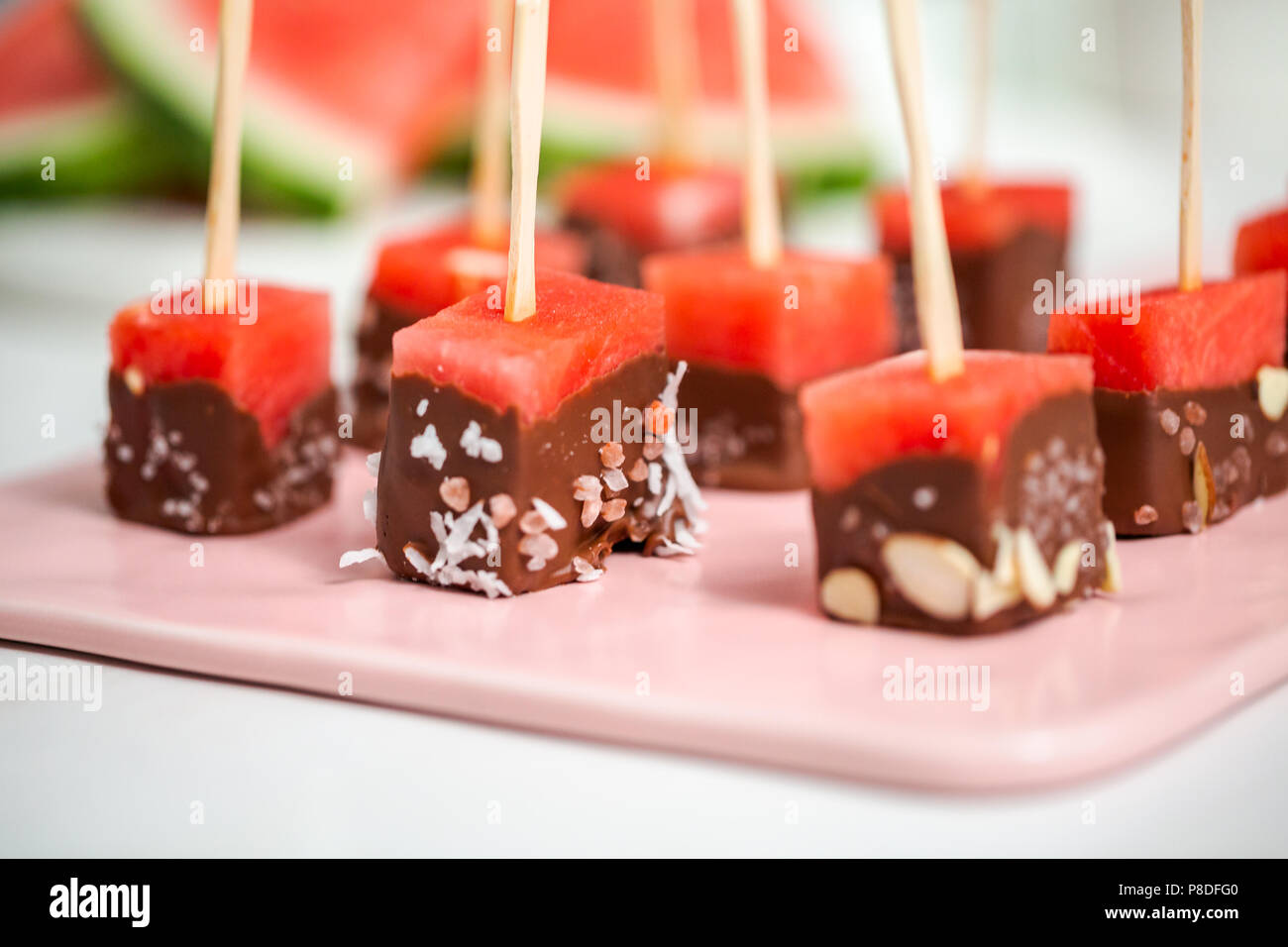 Preparing watermelon appetizers dipped in chocolate and sprinked with