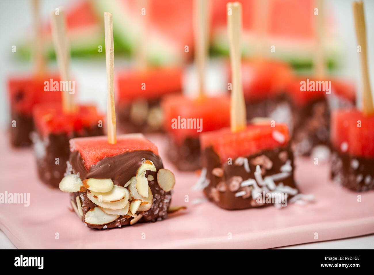 Preparing watermelon appetizers dipped in chocolate and sprinked with